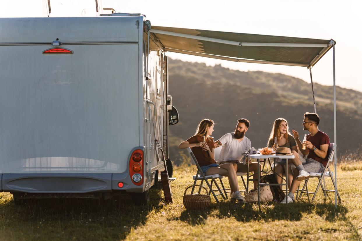 Young happy couples enjoying while talking at picnic table by the camp trailer.