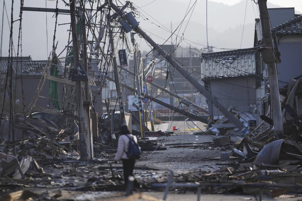 A person walks through a street with debris of damaged and burnt buildings in Wajima in the Noto peninsula, facing the Sea of Japan, northwest of Tokyo, Saturday, Jan. 6, 2024, following Monday's deadly earthquake. (AP Photo/Hiro Komae)