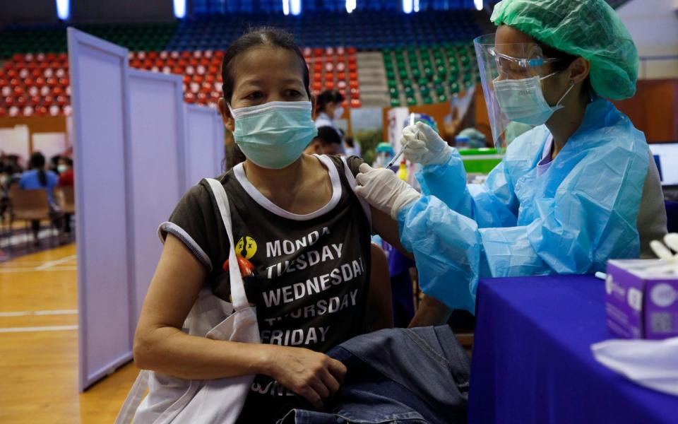 A woman receives a dose of AstraZeneca vaccine at a gymnasium turned vaccination center in Bangkok, Thailand - RUNGROJ YONGRIT/EPA-EFE/Shutterstock