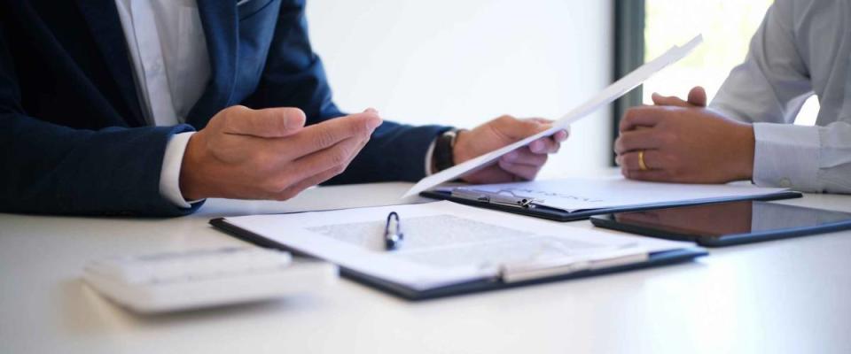 Close up of two men sitting at desk, going over papers