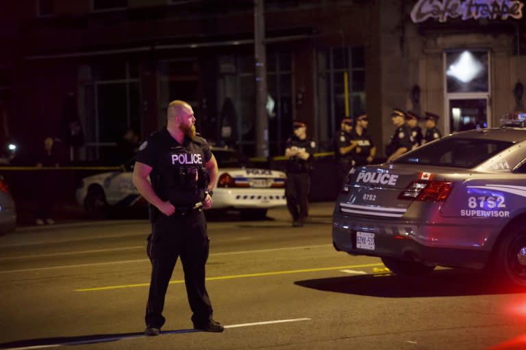 Toronto police stand watch after a shooting left two people dead and 12 wounded in the city