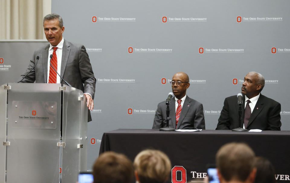 Ohio State football coach Urban Meyer, left, makes a statement during a news conference as university President Michael Drake, center, and athletic director Gene Smith listen in Columbus, Ohio, Wednesday, Aug. 22, 2018. Ohio State suspended Meyer on Wednesday for three games for mishandling domestic violence accusations, punishing one of the sport's most prominent leaders for keeping an assistant on staff for several years after the coach's wife accused him of abuse. Gene Smith was suspended from Aug. 31 through Sept. 16. (AP Photo/Paul Vernon)