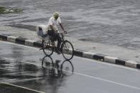 A man rides his bicycle along Marine Drive as rain falls in Mumbai on June 3, 2020. (Photo by PUNIT PARANJPE/AFP via Getty Images)