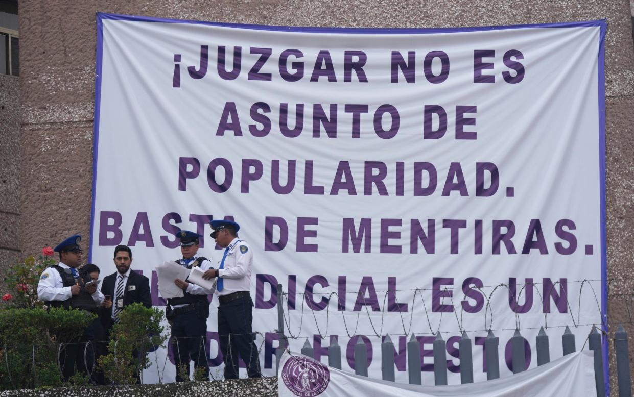 Striking federal court workers stand next to a sign that reads: "Judging is not a popularity issue. Stop the lies. The judiciary is an honest power"