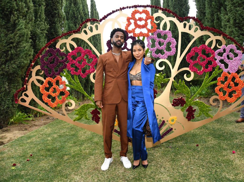 Big Sean and Jhené Aiko stand together in front of a sculpture of a fan