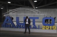 A man waits near a sign for the Auto Shanghai 2019 show in Shanghai Tuesday, April 16, 2019. Automakers are showcasing electric SUVs and sedans with more driving range and luxury features at the Shanghai auto show, trying to appeal to Chinese buyers in their biggest market as Beijing slashes subsidies that have propelled demand. (AP Photo/Ng Han Guan)