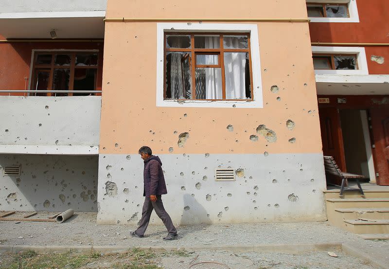 A man walks next to an apartment building that was allegedly damaged by recent shelling in Tartar district