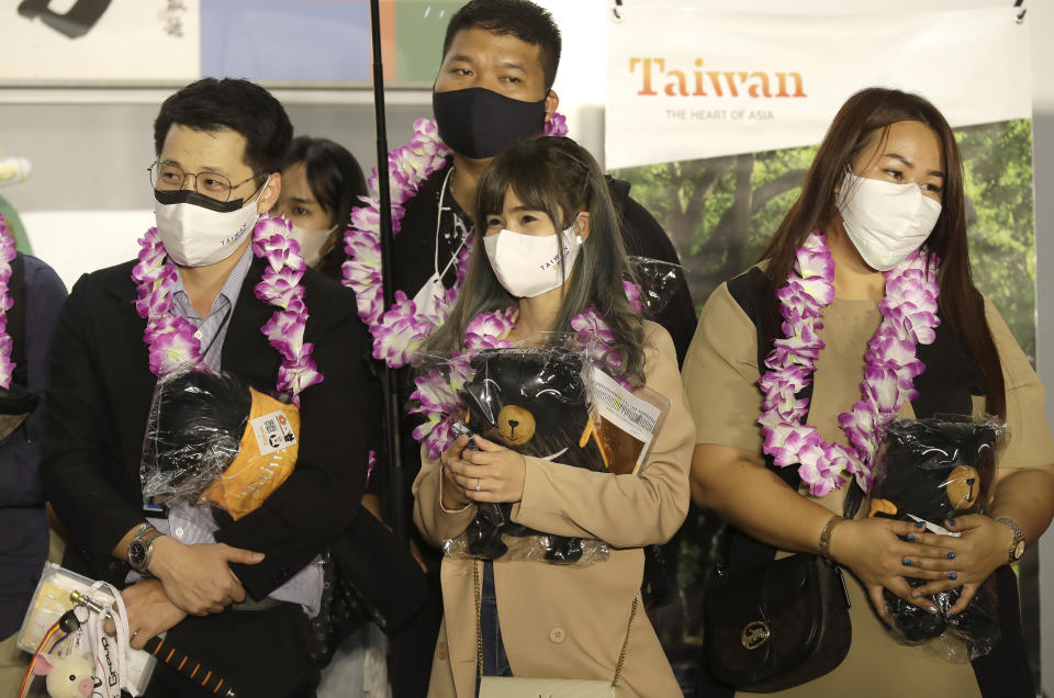 First group of foreign travelers hold souvenirs after arriving at Taoyuan International Airport in Taoyuan, Northern Taiwan, Thursday, Oct. 13, 2022. Taiwan announced that it will end mandatory COVID-19 quarantines for people arriving from overseas beginning Oct. 13. The Central Epidemic Command Center announced that the previous weeklong requirement will be replaced with a seven-day self-monitoring period. (AP Photo/Chiang Ying-ying)