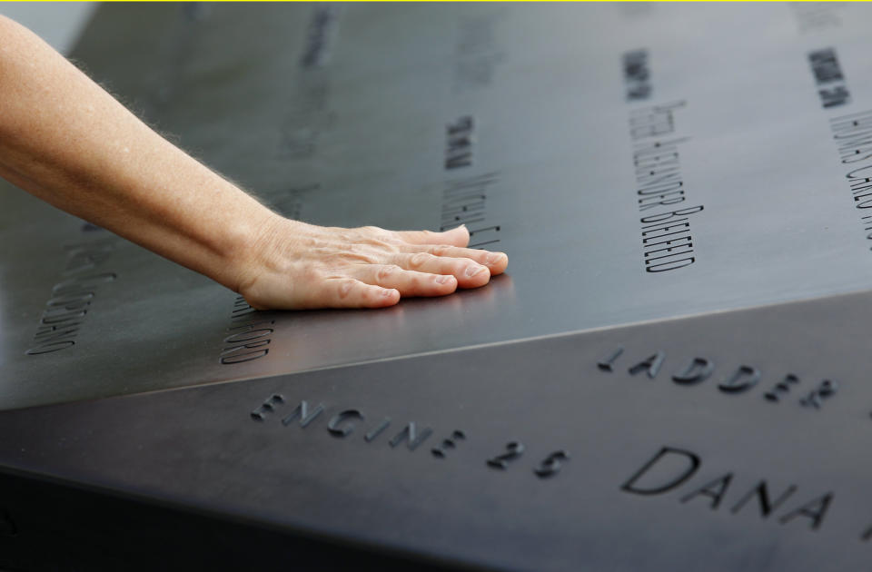 A woman places her hand on a name etched in the wall of one of the pools at the 9/11 memorial plaza in the World Trade Center site in New York Monday, Sept. 12, 2011, on the first day that the memorial was opened to the public. (AP Photo/Mike Segar, Pool)