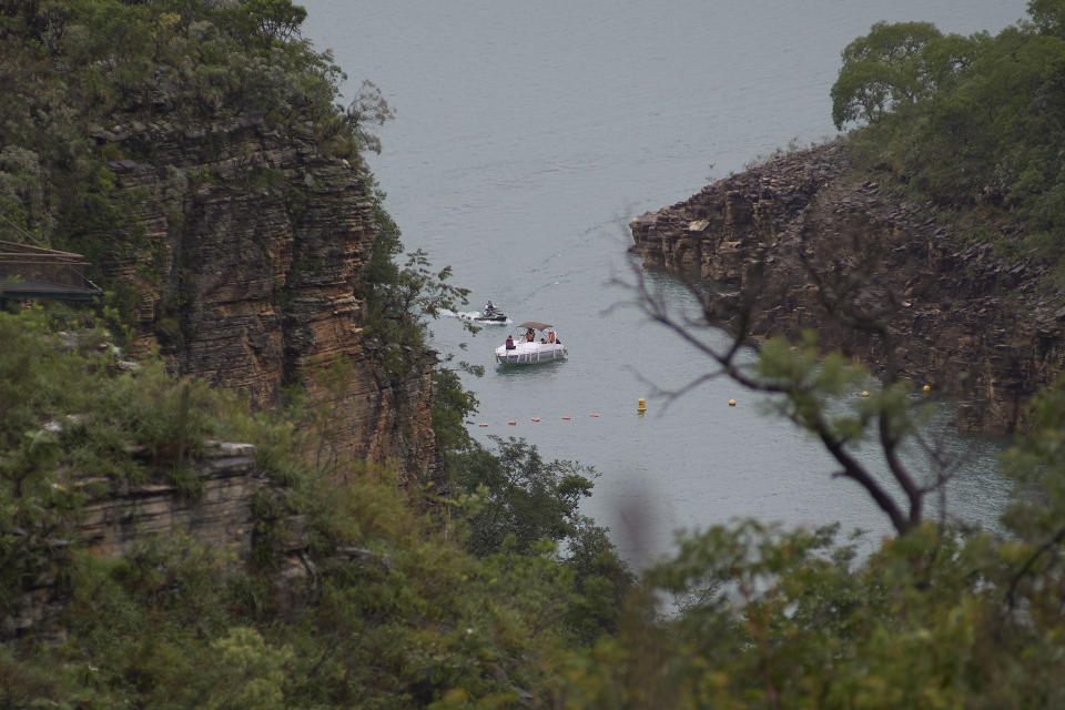 A boat navigates on the Furnas reservoir after a massive slab of rock broke away from a cliff and toppled onto pleasure boaters on Saturday, killing at least seven people near Capitolio city, Brazil, Sunday, Jan. 9, 2022. (AP Photo/Igor do Vale)