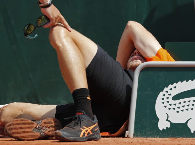 David Goffin lays on the clay after tripping over a rolled-up tarp. (AP)