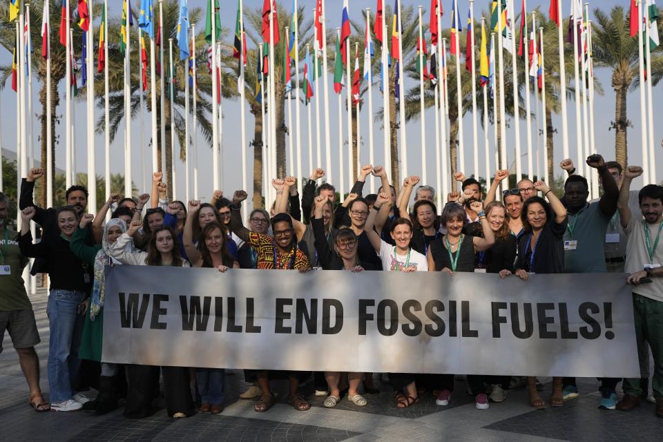 Members of Greenpeace gather for a photo around a sign that reads "we will end fossil fuels" at the COP28 U.N. Climate Summit, Wednesday, Dec. 13, 2023, in Dubai, United Arab Emirates. (AP Photo/Rafiq Maqbool)