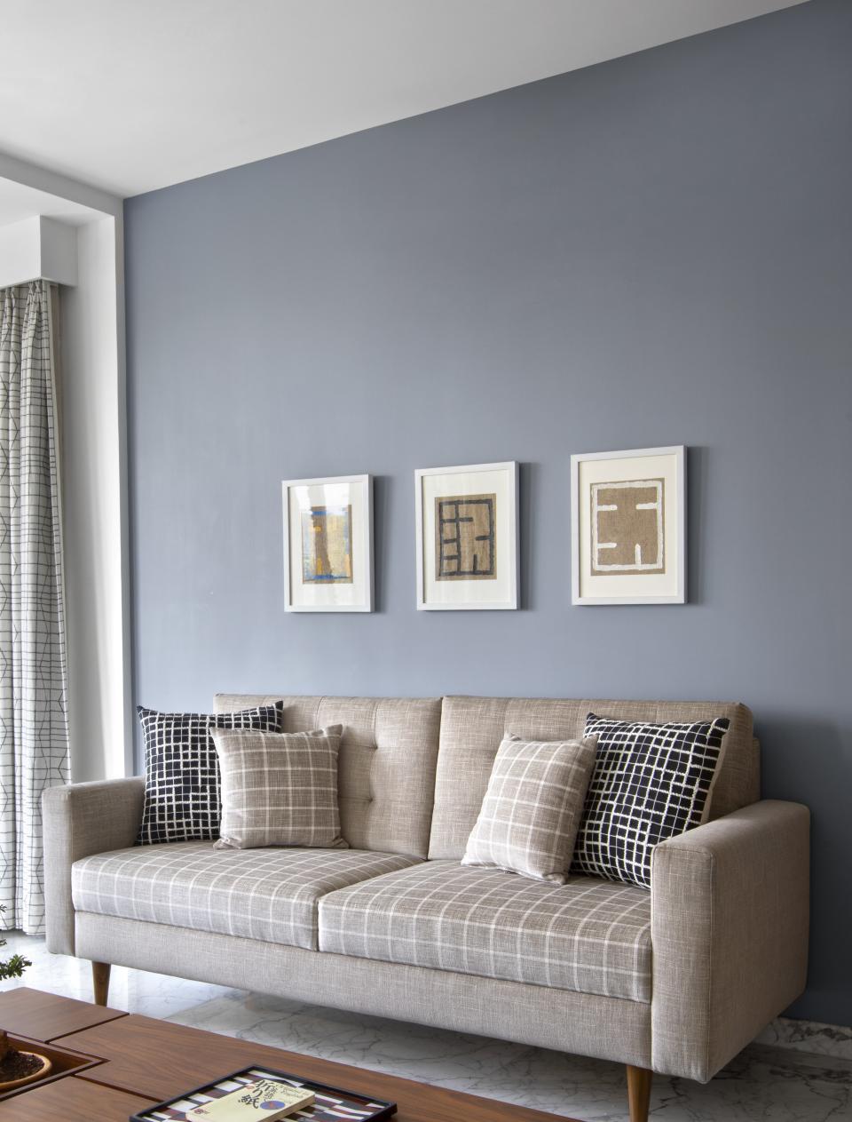 A living room with light blue walls and a grey couch