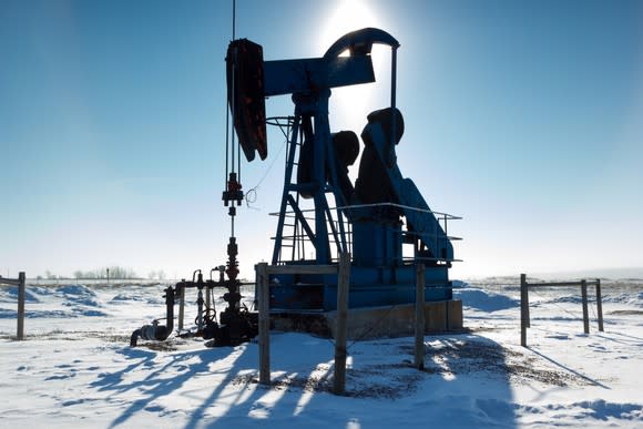 An oil pump with snow on the ground.