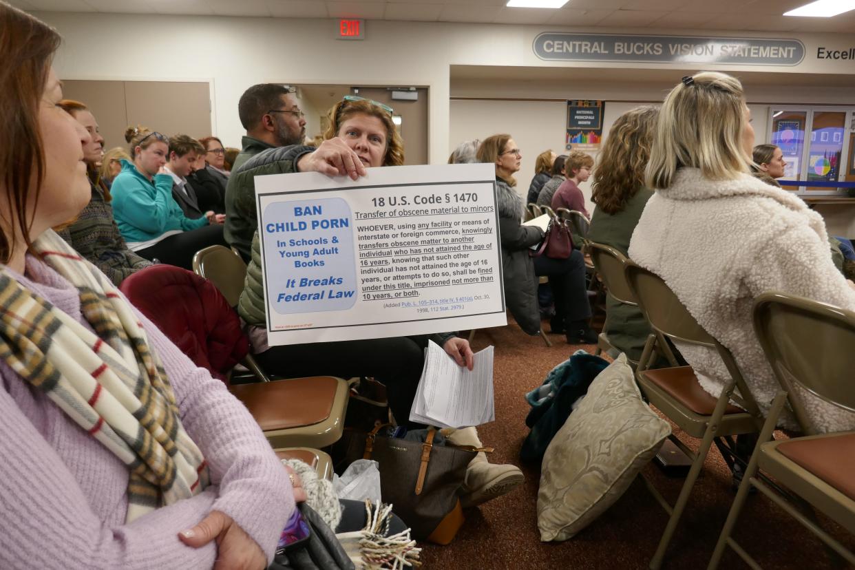 A participant in the Central Bucks School Board meeting Tuesday night holds a placard saying that having books depicting obscene matter in schools where children younger than age 16 attend violates federal law.