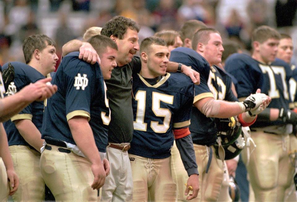 Elmira Notre Dame football coach Mike D'Aloisio puts his arms around Chris Bennett, left, and Mike Meck as the team gathers for the awards ceremony after a state semifinal victory over LeRoy at the Carrier Dome in Syracuse on Nov. 21, 1998.