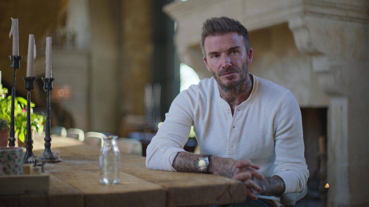  David Beckham sits at a table while being interviewed in Beckham, one of the best Netflix documentaries. 