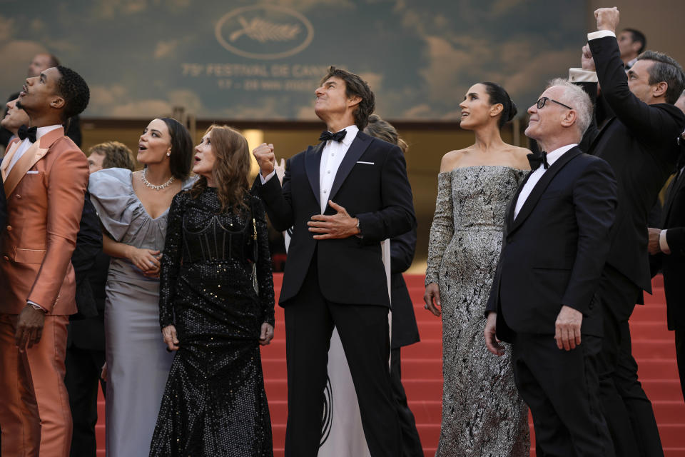 Tom Cruise, en el centro, junto a Greg Tarzan Davis, Keleigh Sperry, Linda Bruckheimer, Jennifer Connelly, el director del festival Thierry Fremaux y Jon Hamm, de izquierda a derecha, ven Alpha Jets Patrouille de Francia sobrevolar la alfombra roja del Festival de Cine de Cannes durante el estreno de "Top Gun: Maverick", el miércoles 18 de mayo de 2022 en el sur de Francia. (Foto AP/Petros Giannakouris)