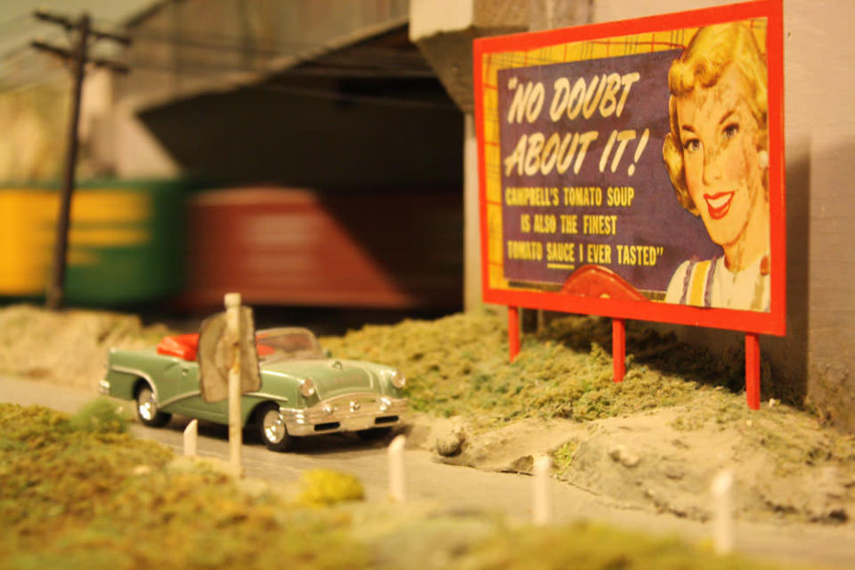 A train speeds by a 50s sign. After 67 years in the Liberty Village location, The Model Railroad Club of Toronto will be moving to make way for a condo.