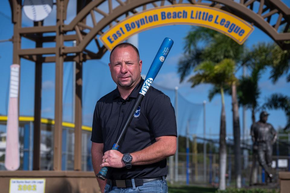 Sports agent and Palm Beach County resident Phil Terrano poses for a portrait holding a baseball bat underneath the arched sign of the East Boynton Little League Complex on Tuesday, February 7, 2023, in Boynton Beach, FL. Terrano, who grew up playing little league baseball at the complex, wants to build a baseball training complex adjacent to the Little League fields that would benefit athletes of all levels.