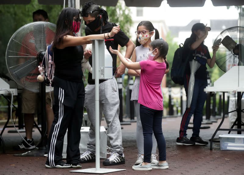 A family use a hand sanitizer station as the National Zoo reopens for socially-distanced patrons for the first time since the start of the coronavirus disease (COVID-19) outbreak in Washington