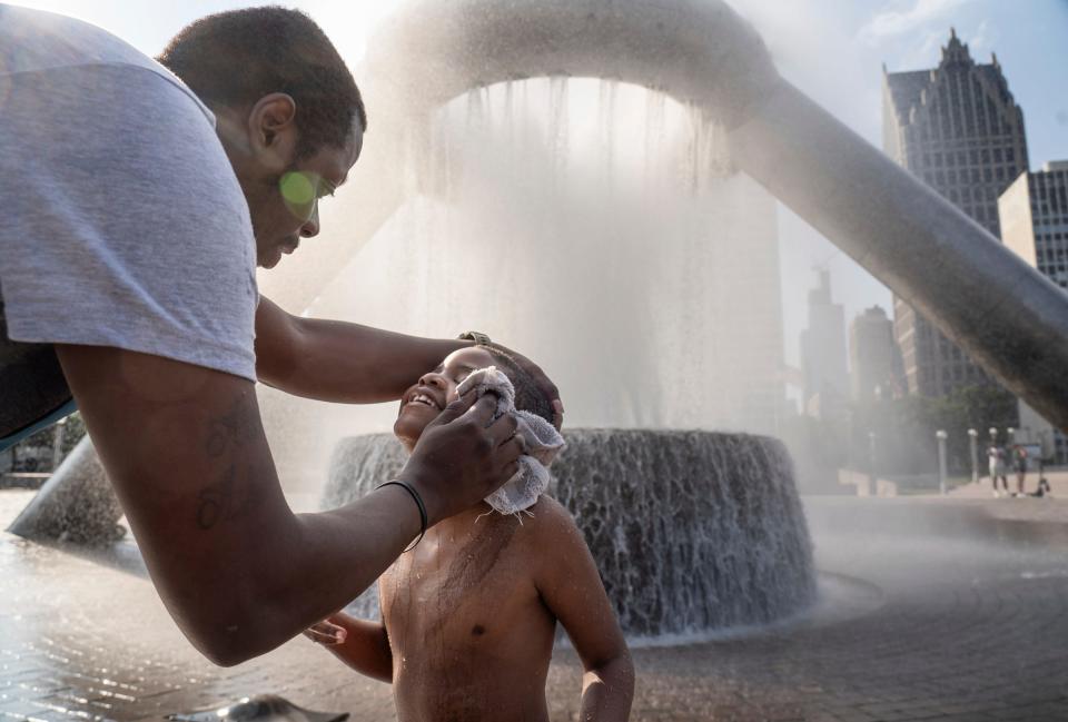 Ray Hawk, of Detroit, wipes water from the face of his son Royce Mauldin, of Detroit, after he successfully made it to the center of Dodge Fountain in Hart Plaza after several attempts while finding relief from the heat in downtown Detroit on Monday, June 17, 2024.