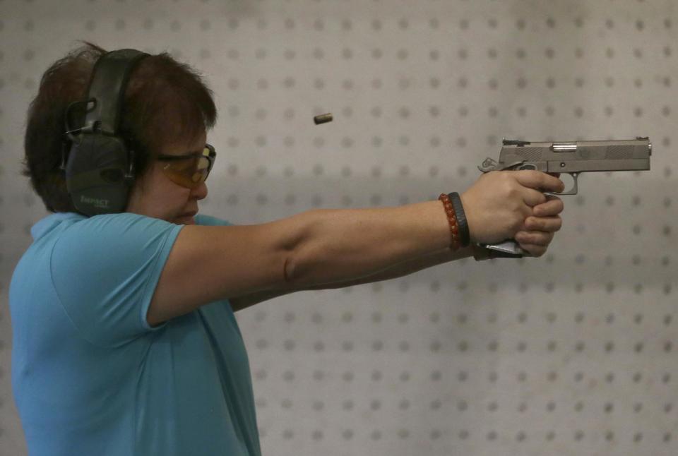 In this Feb. 9, 2014 photo, Bureau of Internal Revenue Commissioner Kim Henares fires her pistol during target practice in a firing range at suburban Mandaluyong city, east of Manila, Philippines. The 53-year-old straight-talking chief has shifted her agency into “law enforcement mode” with an aggressive anti-tax evasion campaign to catch cheats and raise collections. Henares is a lawyer and accountant whose hobbies include weekly trips to the firing range where she shoots off automatic pistols and assault rifles. Shooting has become one of her favorite pastimes since she was appointed in July 2010 by President Benigno Aquino III, a gun aficionado who introduced her to the sport. (AP Photo/Bullit Marquez)