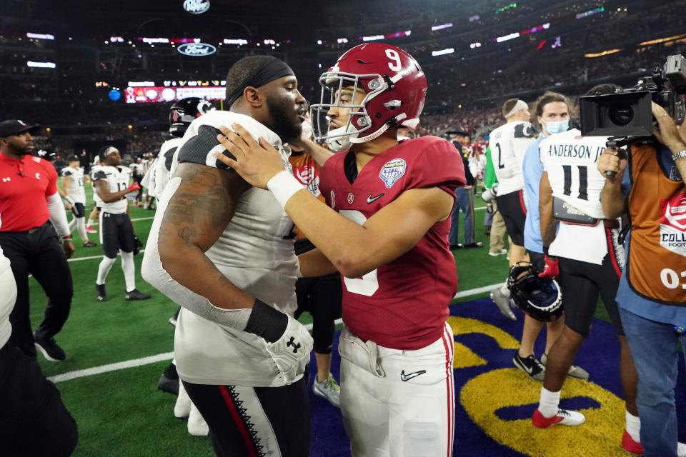 Alabama quarterback Bryce Young (9) hugs Cincinnati defensive lineman Malik Vann (42) after the Cotton Bowl NCAA College Football Playoff semifinal game Dec. 31, 2021.