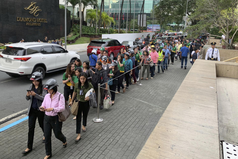 Office employees, some wearing hard hats, file out of their building following a magnitude 5.5 that rocked some areas of the country's north, including in the capital, that also briefly disrupted train services Friday, Sept. 13, 2019 in Manila, Philippines. The Philippine Institute of Seismology and Volcanology says Friday's quake was centered about 40 kilometers northeast of the coastal town of Burdeos in northeastern Quezon province and was caused by movement in a local fault at a shallow depth of 10 kilometers (6 miles). There were no immediate reports of injuries or damages. (AP Photo/Bullit Marquez)