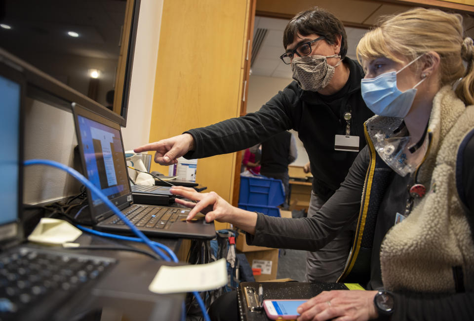 In this photo provided by the University of Vermont Health Network, IT staff help clinical providers set up new computers at the University of Vermont Medical Center in Burlington, Vt., on Friday, Nov. 20, 2020. After the Oct. 28 attack forced a shutdown of the hospital’s electronic medical records and other key systems, the IT department, with support from the Vermont National Guard’s cyber team, scanned thousands of computers for malware and replaced machines for hospital staff. (Ryan Mercer/University of Vermont Health Network via AP)