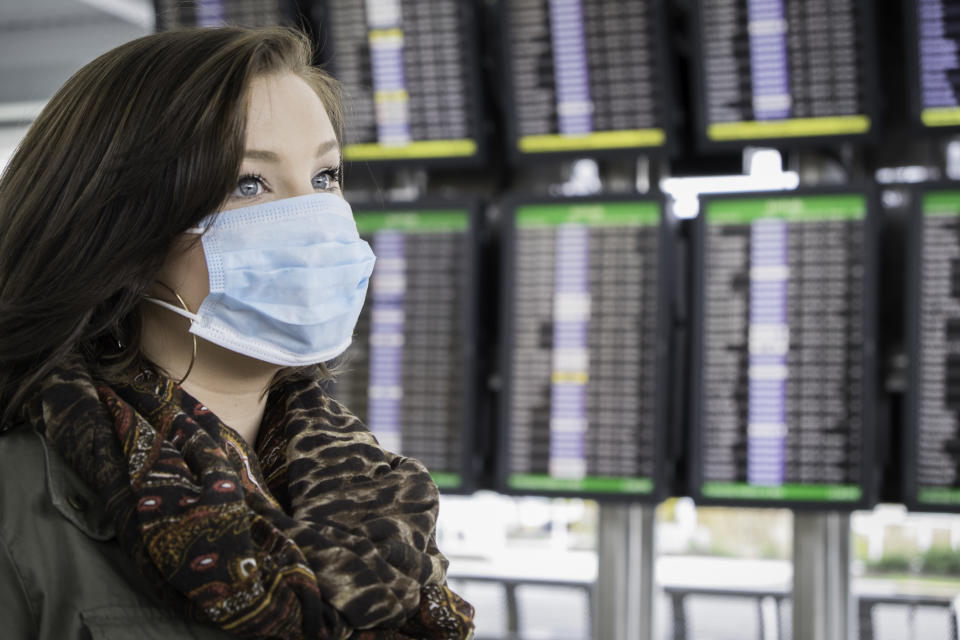 An attractive female wears a mask at the airport, possibly fearful of coronavirus.