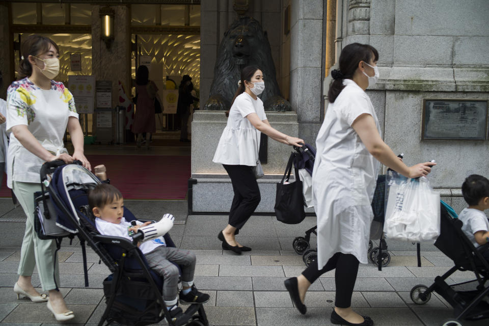 Mothers wearing face masks with their children come out of a department store in Tokyo during a state of emergency on Thursday, Sept. 30, 2021. On Friday, Oct. 1, 2021, Japan fully came out of a coronavirus state of emergency for the first time in more than six months as the country starts gradually easing virus measures to help rejuvenate the pandemic-hit economy as the infections slowed.(AP Photo/Hiro Komae)