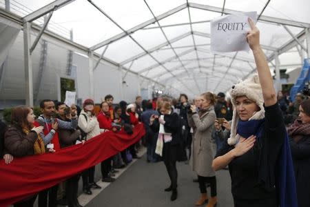 A woman holds a placard which reads "equity" during a giant red line demonstration as an act of climate disobedience during the World Climate Change Conference 2015 (COP21) at Le Bourget, near Paris, France, December 11, 2015. REUTERS/Stephane Mahe