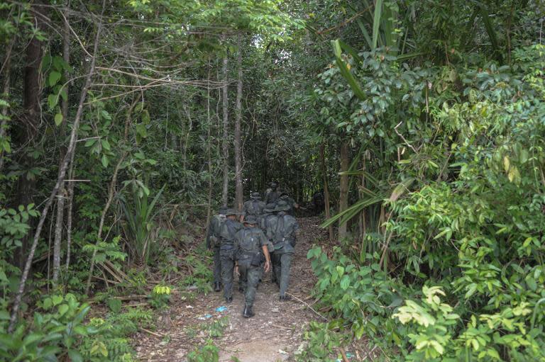Royal Malaysian Police personnel walk towards the dense jungle area in Wang Kelian that leads to an abandoned migrant camp used by people-smugglers, on May 28, 2015