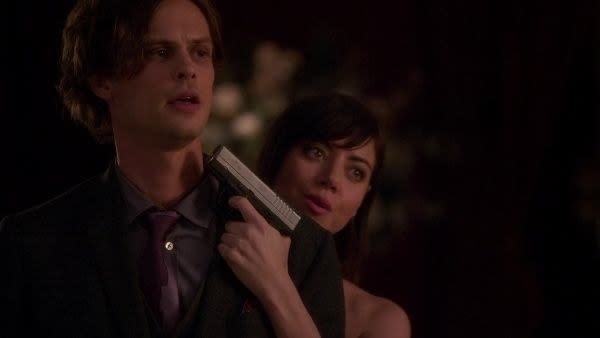 Cat holding a gun up to Spencer's head