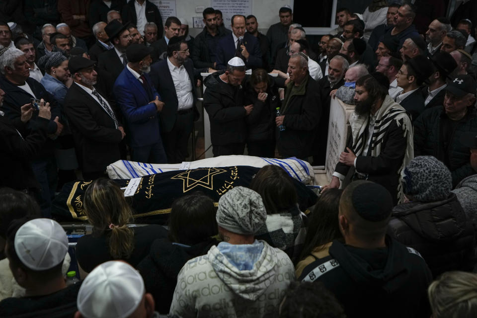 Mourners gather around the bodies of Israeli couple Eli Mizrahi and his wife, Natalie, victims of a shooting attack Friday in east Jerusalem, during their funeral at the cemetery in Beit Shemesh, Israel, early Sunday, Jan. 29, 2023. On Friday, a Palestinian gunman opened fire outside an east Jerusalem synagogue, killing the couple and another five people, including a 70-year-old woman, and wounding three others before he was shot and killed by police, officials say. It was the deadliest attack on Israelis since 2008 and raised the likelihood of more bloodshed. (AP Photo/Ariel Schalit)