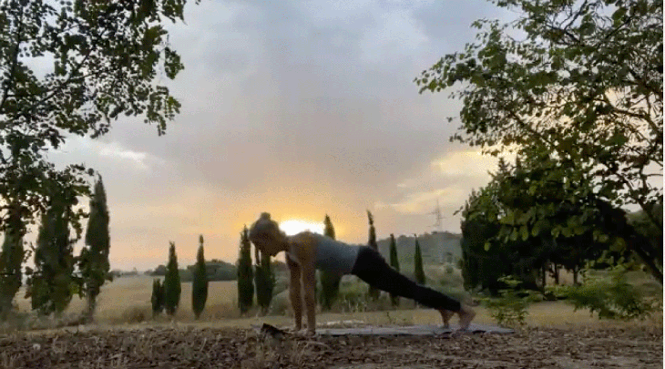 Woman practicing yoga outside at sunrise doing top of a push-up