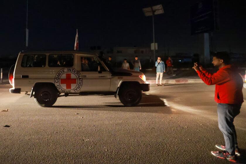 TOPSHOT - A man takes picture with his mobile of International Red Cross vehicles reportedly carrying hostages released by Hamas as they cross the Rafah border point in the Gaza Strip towards Egypt from where they would be flown to Israel to be reunited with their families, on November 24, 2023. After 48 days of gunfire and bombardment that claimed thousands of lives, a four-day truce in the Israel-Hamas war began on November 24 with 50 hostages set to be released in exchange for 150 Palestinian prisoners. (Photo by MOHAMMED ABED / AFP) (Photo by MOHAMMED ABED/AFP via Getty Images)