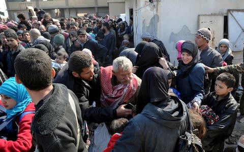 Syrian civilians with their belongings as they flee from fighting between the Syrian government forces and rebels - Credit: SANA