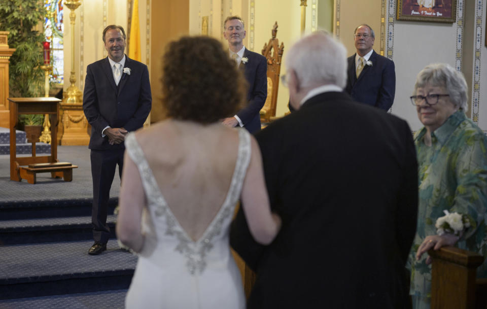 Before Tropical Storm Barry makes landfall, Associated Press staff photographer Gerald Herbert, background left, watches his bride, Lucy Sikes, walk down the aisle at Mater Dolorosa Catholic Church in New Orleans, Friday, July 12, 2019. Originally scheduled for Saturday, the couple moved their nuptials up a day to avoid the arrival of Tropical Storm Barry. (Max Becherer/The Advocate via AP)