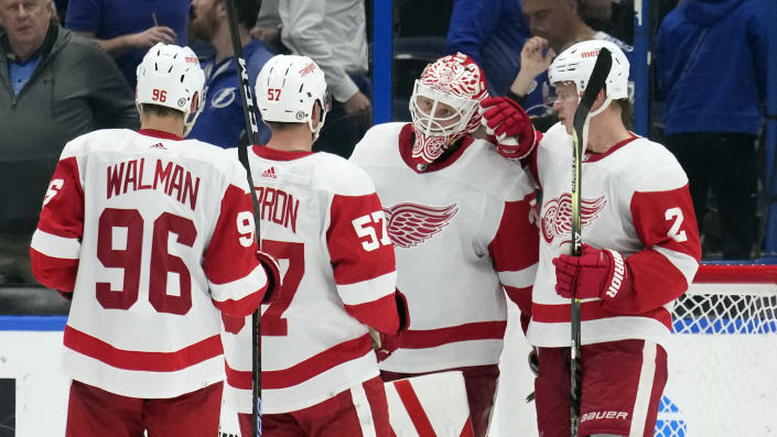 Detroit Red Wings goaltender Ville Husso (35) celebrates with teammates, including defenseman Olli Maatta (2), left wing David Perron (57) and defenseman Jake Walman (96) after an NHL hockey game against the Tampa Bay Lightning Tuesday, Dec. 6, 2022, in Tampa, Fla. (AP Photo/Chris O'Meara)