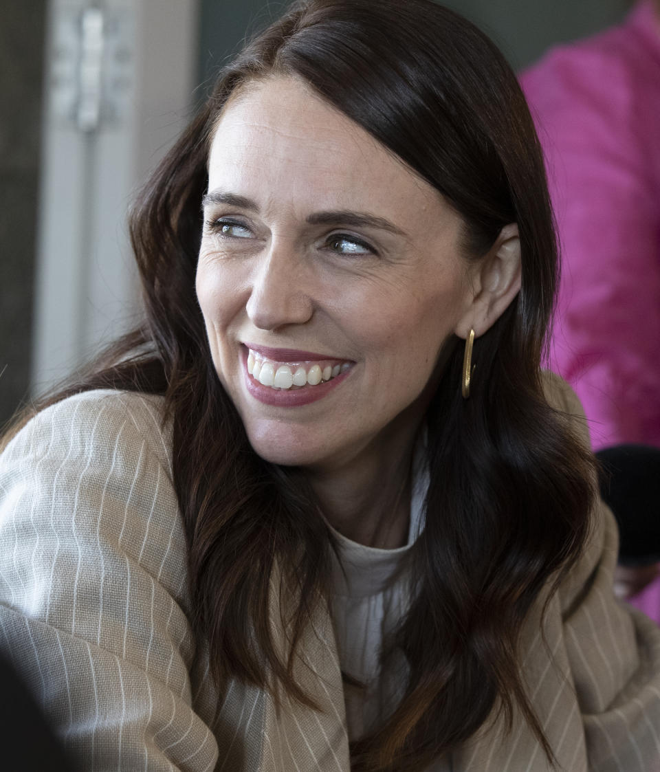 New Zealand Prime Minister Jacinda Ardern reacts as she talks with colleagues at a cafe in Auckland, New Zealand, Sunday, Oct. 18, 2020. Ardern has won a second term in office in an election landslide of historic proportions. (AP Photo/Mark Baker)