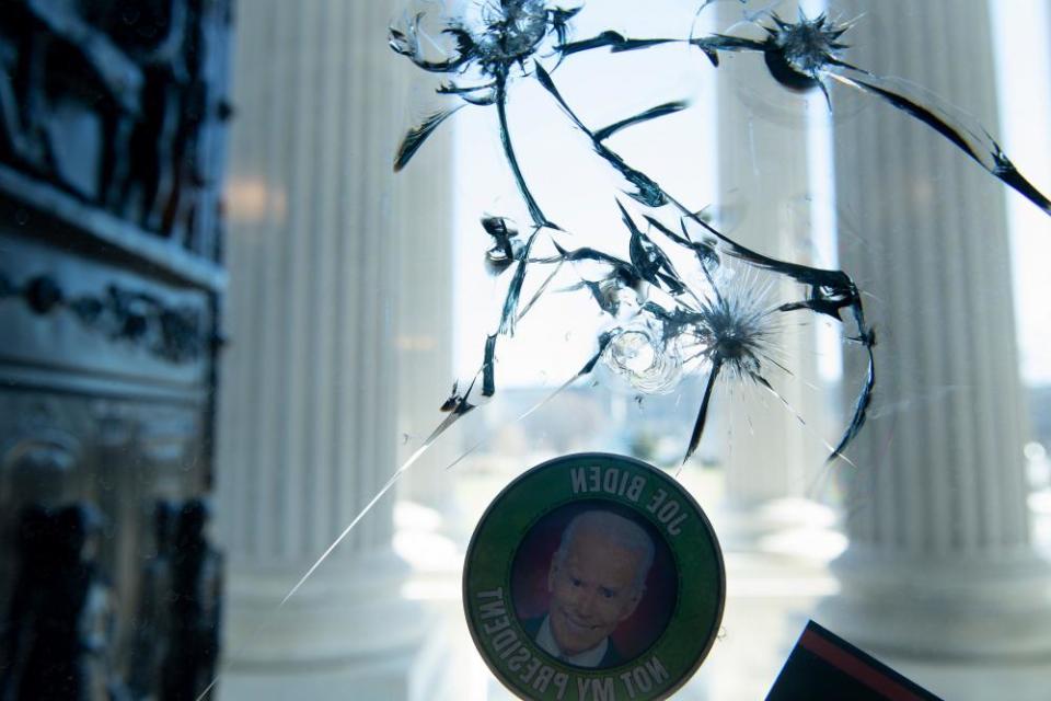 An anti-Biden sticker is seen on a cracked window a day after a pro-Trump mob broke into the US Capitol.