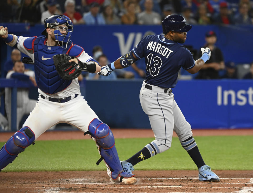 Toronto Blue Jays catcher Danny Jansen, left, throws to second base in an effort to beat a steal, but is hit on the backswing by Tampa Bay Rays Manuel Margot (13) sending the runner back to first in the third inning of the first baseball game of a doubleheader in Toronto, Tuesday, Sept. 13, 2022. (Jon Blacker/The Canadian Press via AP)