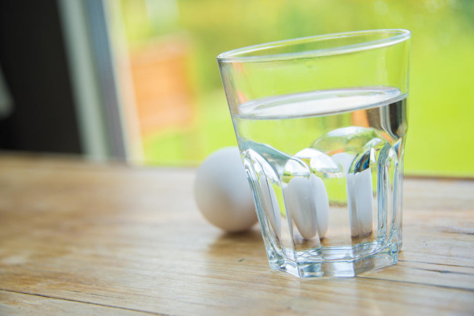 two eggs and a glass of water on a wooden table