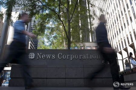 Passers-by walk near the News Corporation building in New York June 28, 2012. REUTERS/Keith Bedford