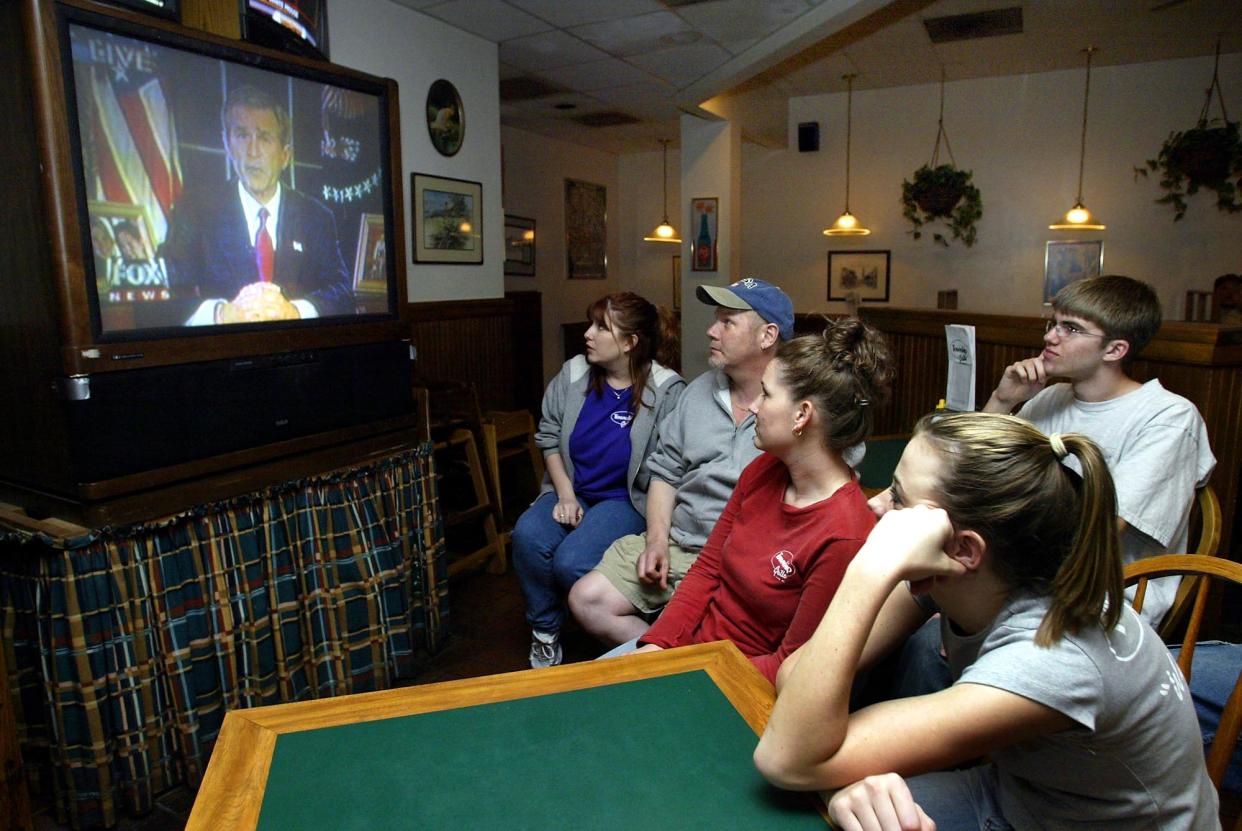 Employees and customers at the Township Grille in Matthews, N.C., watch as President Bush announces the beginning of U.S.-led military action in Iraq late on the evening of March 19, 2003.