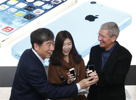 Apple Inc. CEO Tim Cook (R) and China Mobile's Chairman Xi Guohua (L) with iPhones pose with a customer at an event celebrating the launch of Apple's iPhone on China Mobile's network at a China Mobile shop in Beijing January 17, 2014. REUTERS/Kim Kyung-Hoon