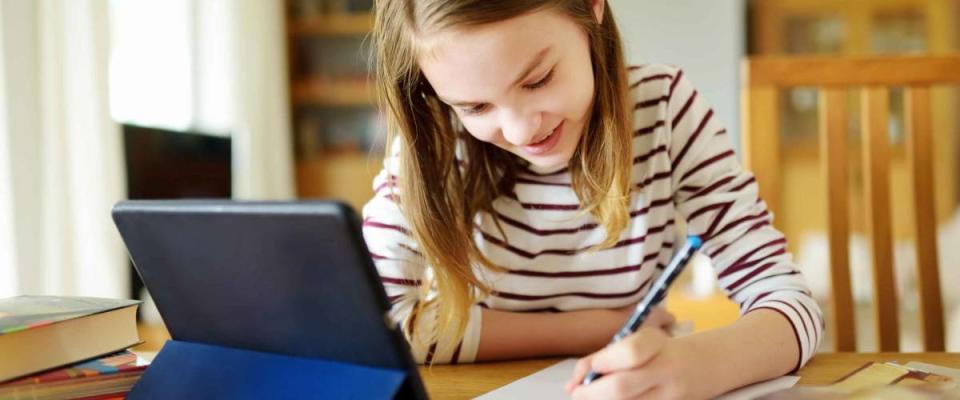 Preteen schoolgirl doing her homework with digital tablet at home.