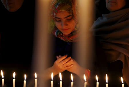 A girl prays for the victims of a militant attack on the Bacha Khan University, during a candle light vigil in Peshawar, Pakistan January 20, 2016. REUTERS/Khuram Parvez